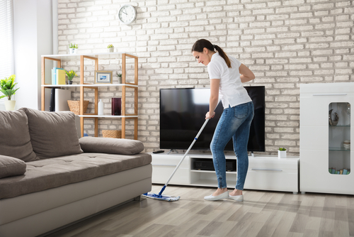 woman cleaning hard wood floor in a modern cozy living room